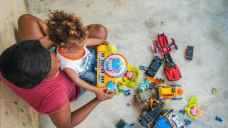 Una madre y su bebé juegan en el suelo de hormigón de su casa.