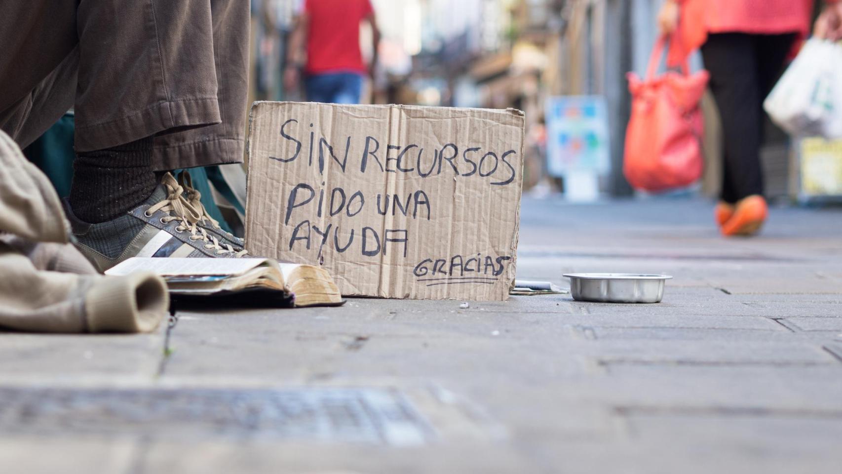 Un vagabundo pide limosna en la calle.