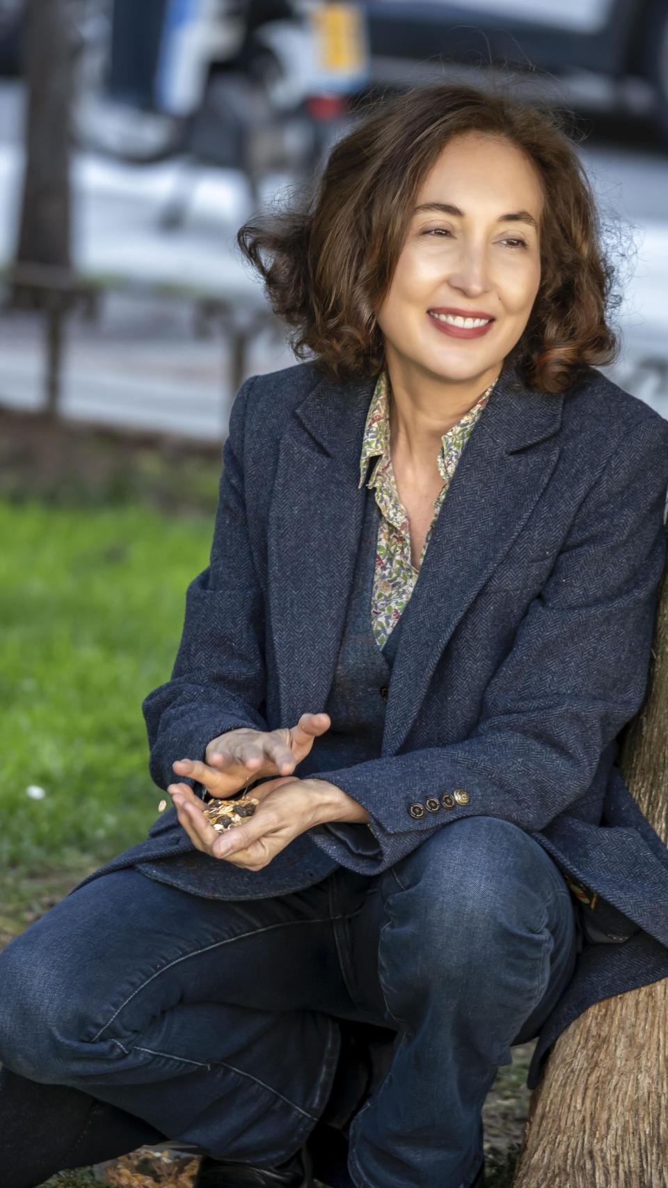 La escritora con alpiste en las manos para alimentar a los gorriones.