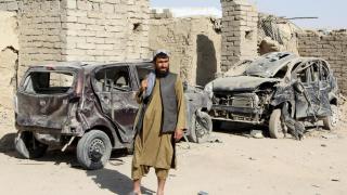 A Taliban fighter stands next to vehicles destroyed during an airstrike in Afghanistan before the ceasefire came into effect.