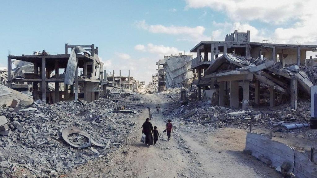 Un grupo de personas caminan entre escombros en un barrio de Ciudad de Gaza.