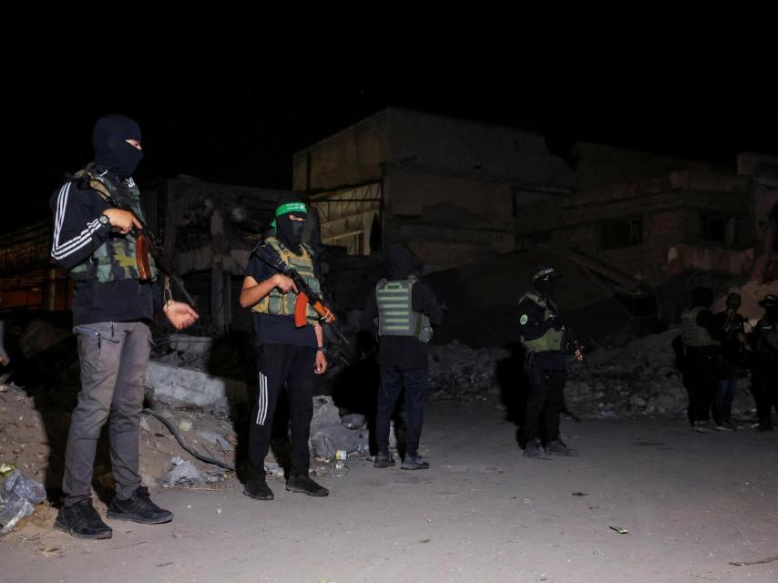 Militantes de Hamás hacen guardia mientras vehículos de la Cruz Roja recogen el pasado 15 de octubre los cadáveres de rehenes israelíes.