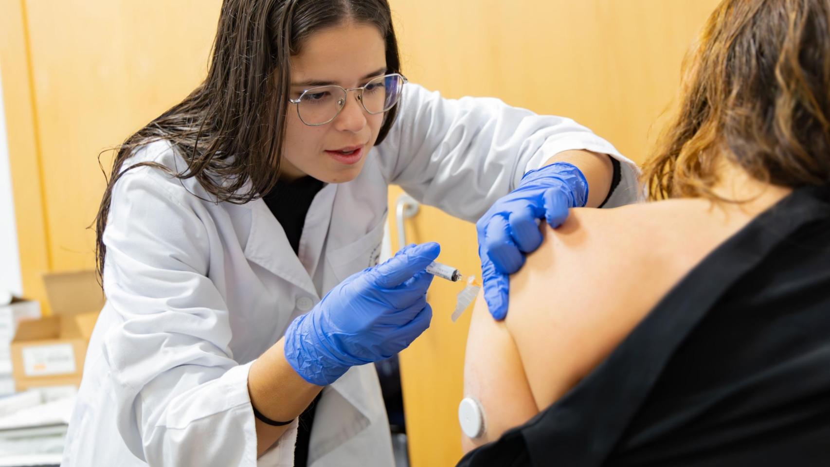 Una profesional sanitaria poniendo una vacuna.