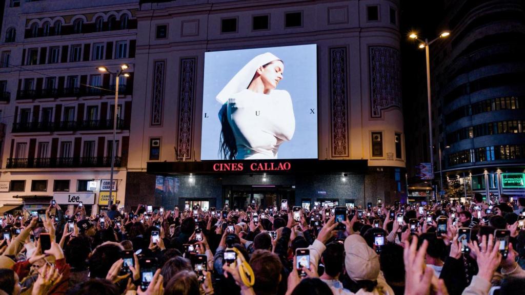 Decenas de personas observan la portada del nuevo álbum de Rosalía, 'Lux', en la plaza de Callao este lunes.