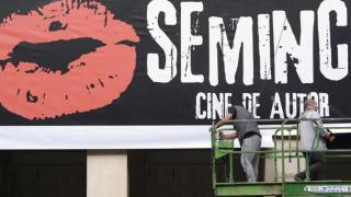 Dos operarios colocando el cartel de la Seminci en Valladolid.