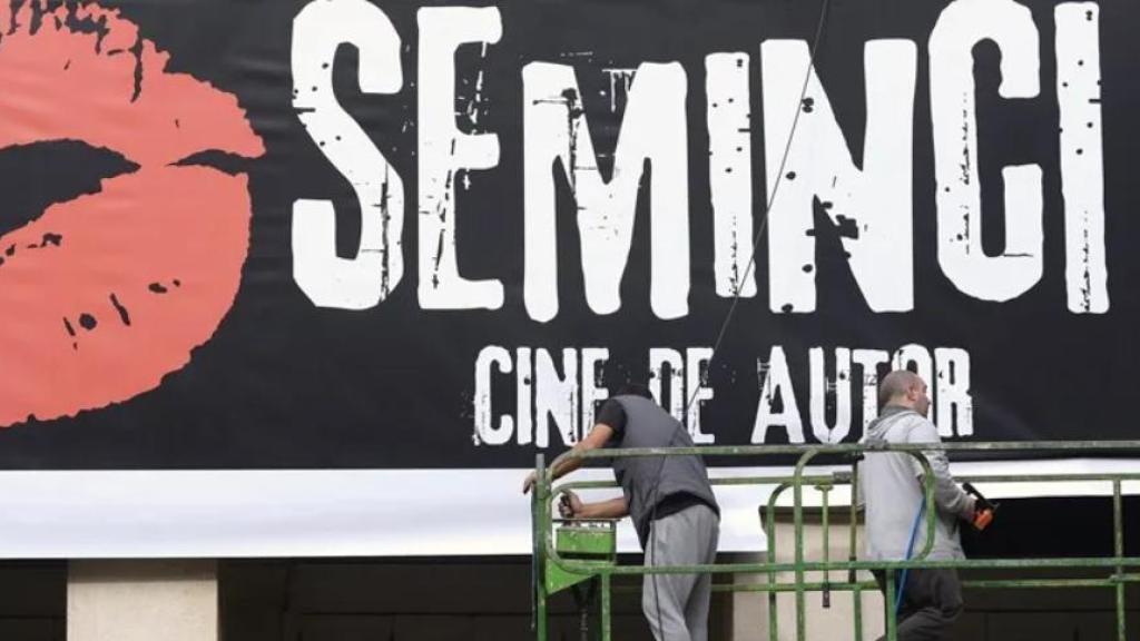 Dos operarios colocando el cartel de la Seminci en Valladolid.