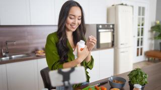 Imagen de archivo de una mujer tomando complementos alimenticios en la cocina.