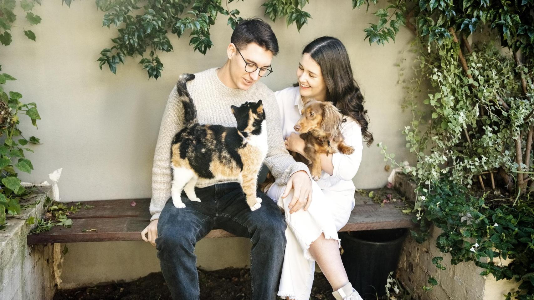 Un chico y una chica con un perro y un gato.