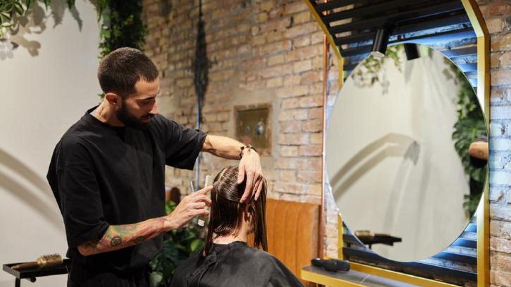 Peluquero cortando el cabello a su clienta.
