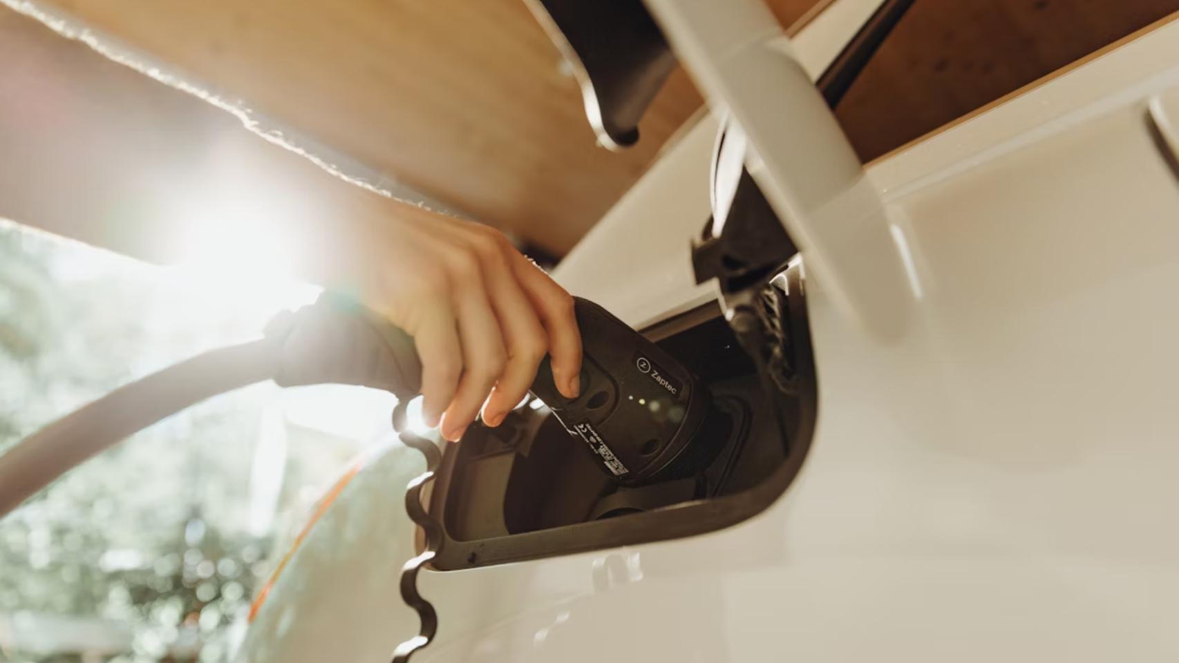 Una persona cargando un coche eléctrico.