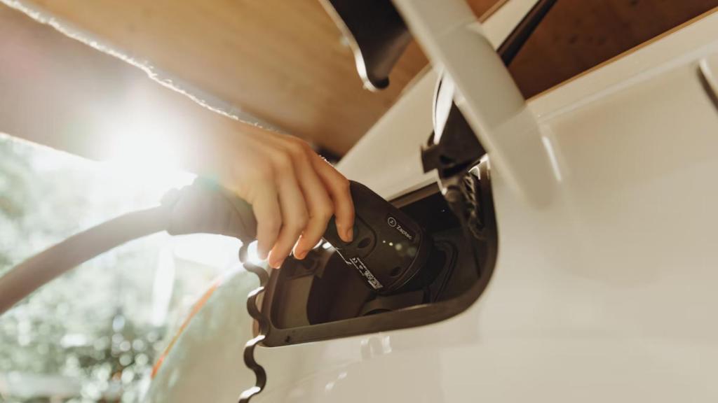 Una persona cargando un coche eléctrico.