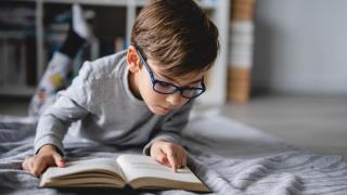 Un niño acostado en el suelo leyendo un libro.