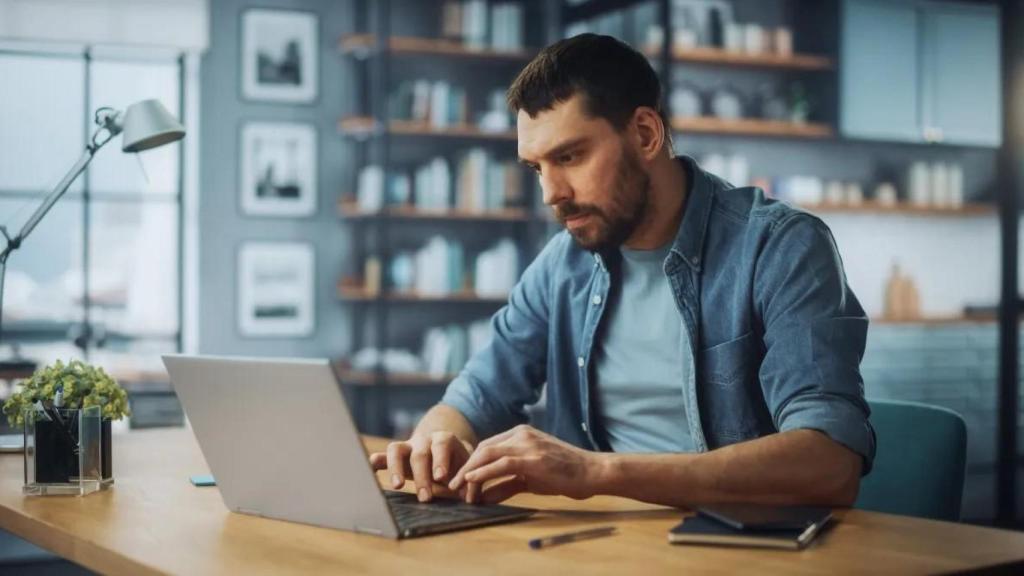Un trabajador utilizando un ordenador desde la mesa de su casa.