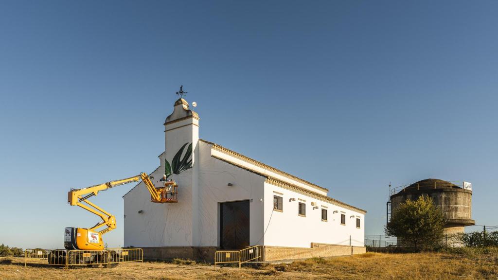 El pintor Manuel León subido en la grúa mientras pinta el mural en Villanueva del Ariscal.
