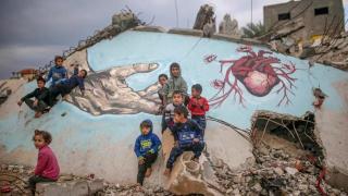 Imagen de archivo de niños palestinos desplazados internamente jugando junto a un mural en Deir Al Balah (Gaza).