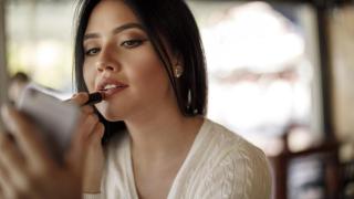 Mujer pintándose los labios.