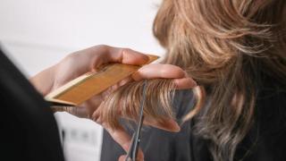 Peluquera cortando el pelo a su clienta.