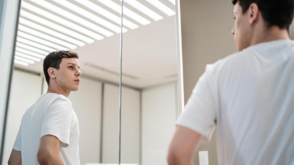 Imagen de archivo de un chico mirándose en un espejo.