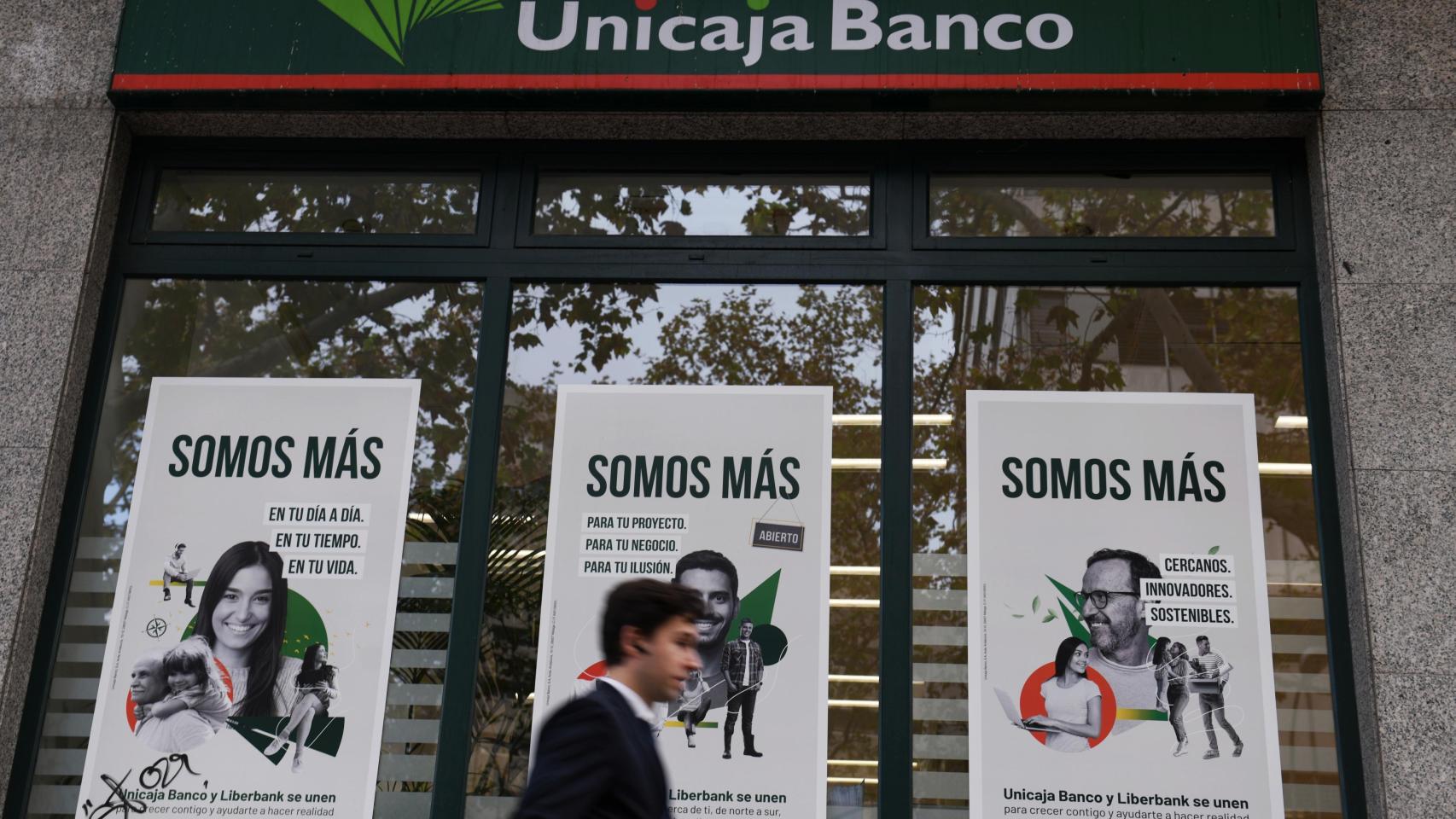 Una persona camina frente a una oficina de Unicaja.