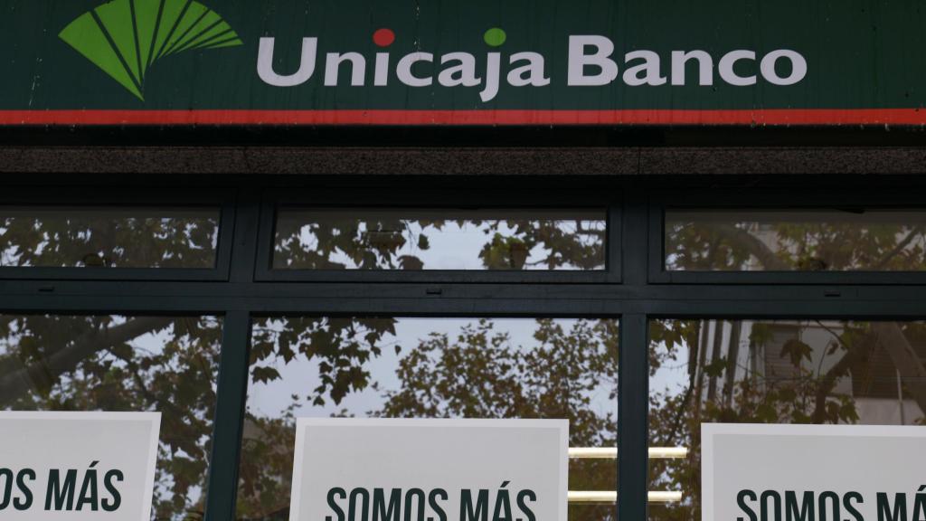 Una persona camina frente a una oficina de Unicaja.