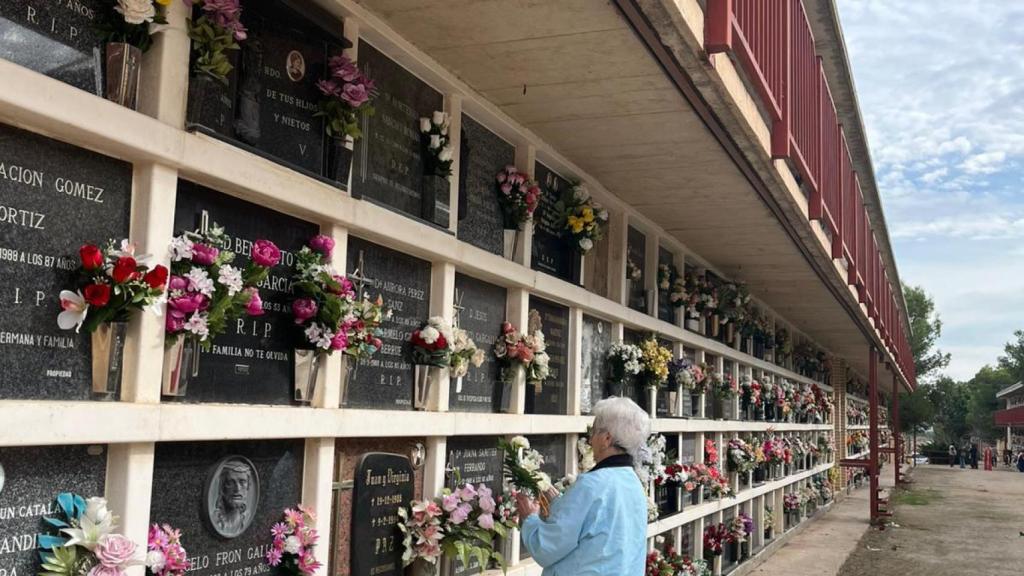 Una mujer poniendo flores en el cementerio de Torrero de Zaragoza.