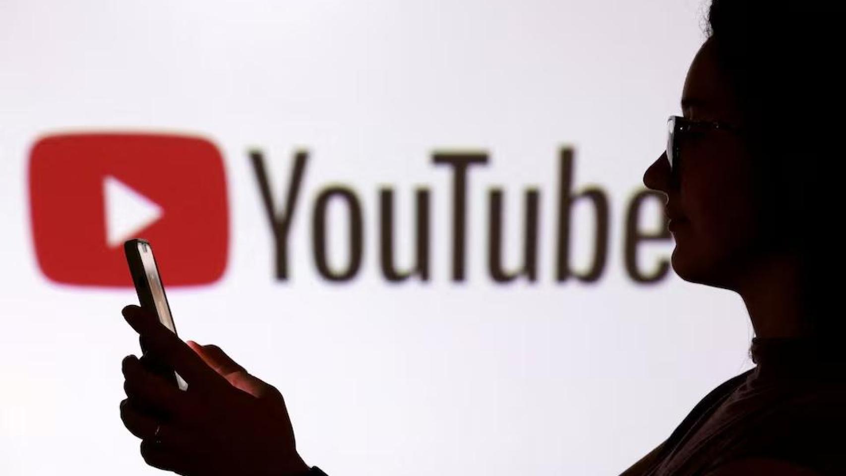 Un joven se hace un selfi delante del logo de YouTube.