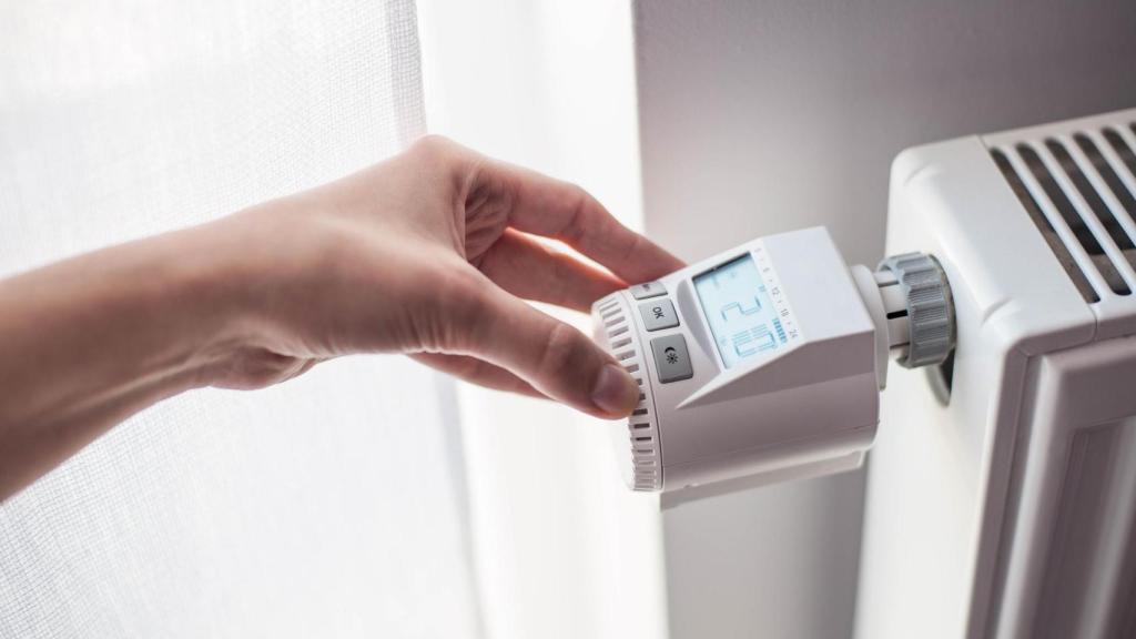 Una persona ajustando la temperatura de un radiador con termostato.