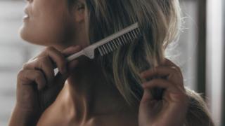 Mujer cepillándose el cabello.
