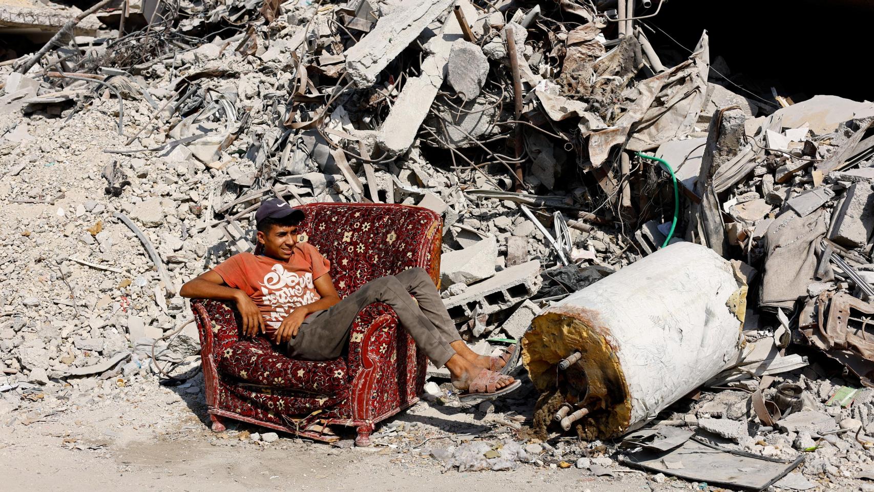 Un joven palestino sentado en un sillón entre las ruinas de Ciudad de Gaza.