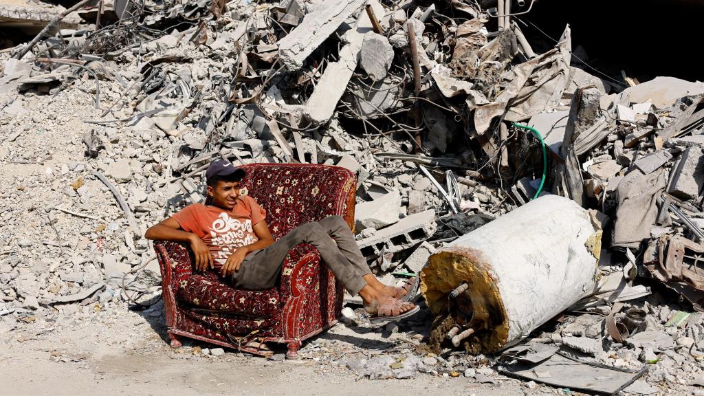 Un joven palestino sentado en un sillón entre las ruinas de Ciudad de Gaza.