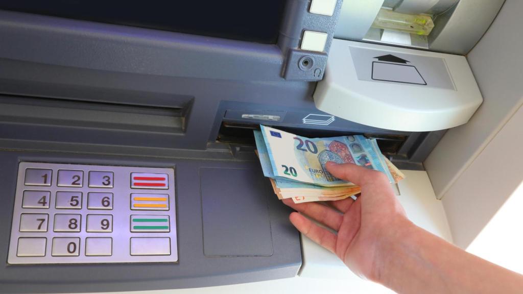 Una persona retira dinero en efectivo de un cajero automático