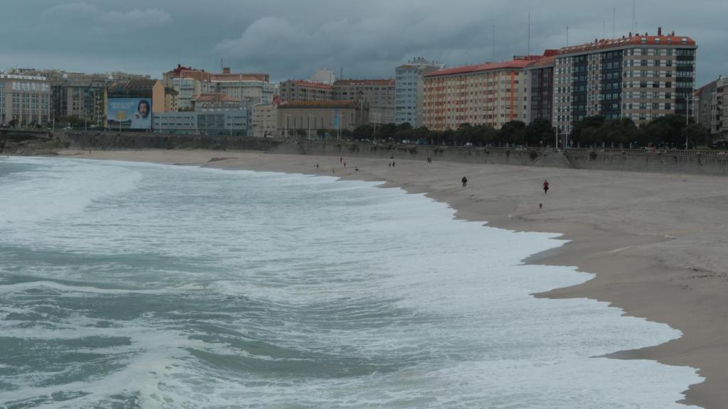Imagen de archivo de la playa del Orzán de A Coruña con fuerte oleaje y ciudadanos paseando.