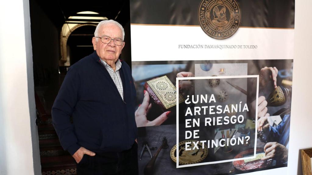El artesano Mariano San Félix (86 años) junto a un cartel de la Fundación Damasquinado de Toledo.