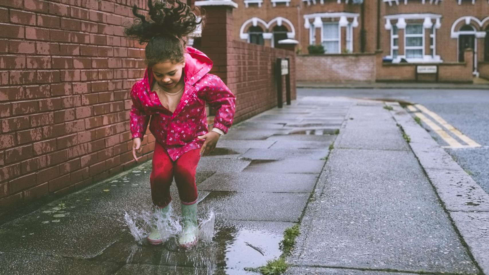 Una niña jugando sola en la ciudad.