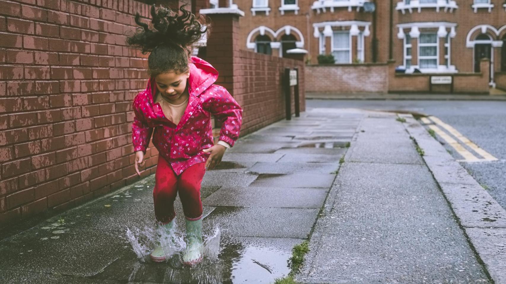 Una niña jugando sola en la ciudad.