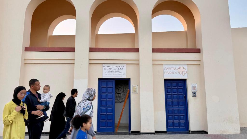 Una familia camina delante de la última iglesia española en el Sáhara Occidental mientras dentro se celebra la Adoración al Santísimo.