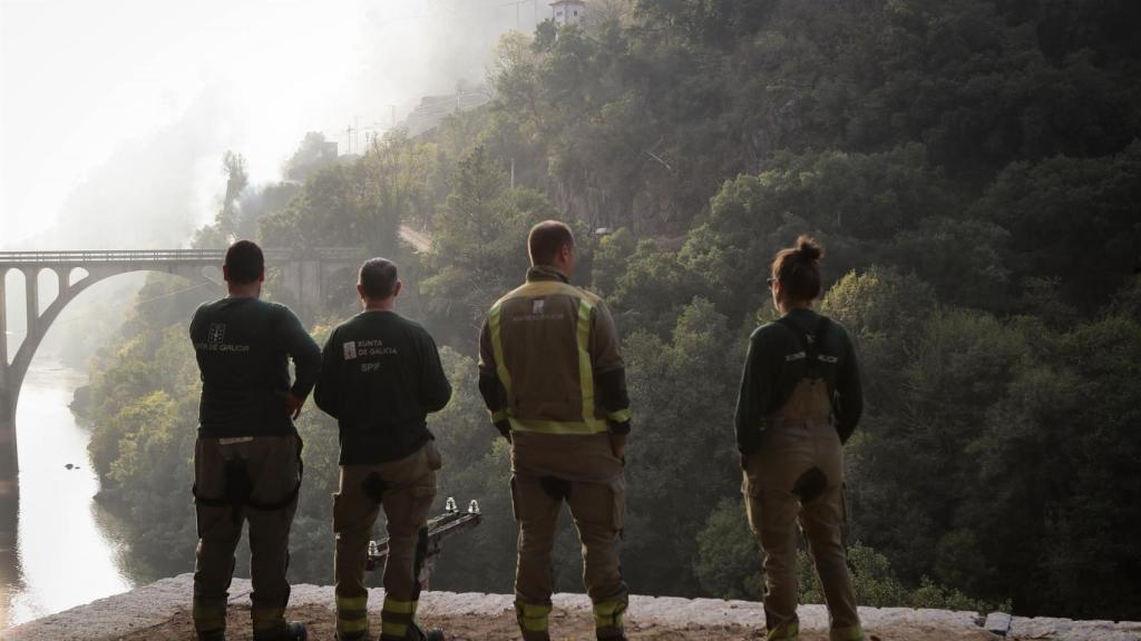 Cuatro personas observan el terreno calcinado, a 20 de septiembre de 2025, en A Barca, en Sober (Lugo)