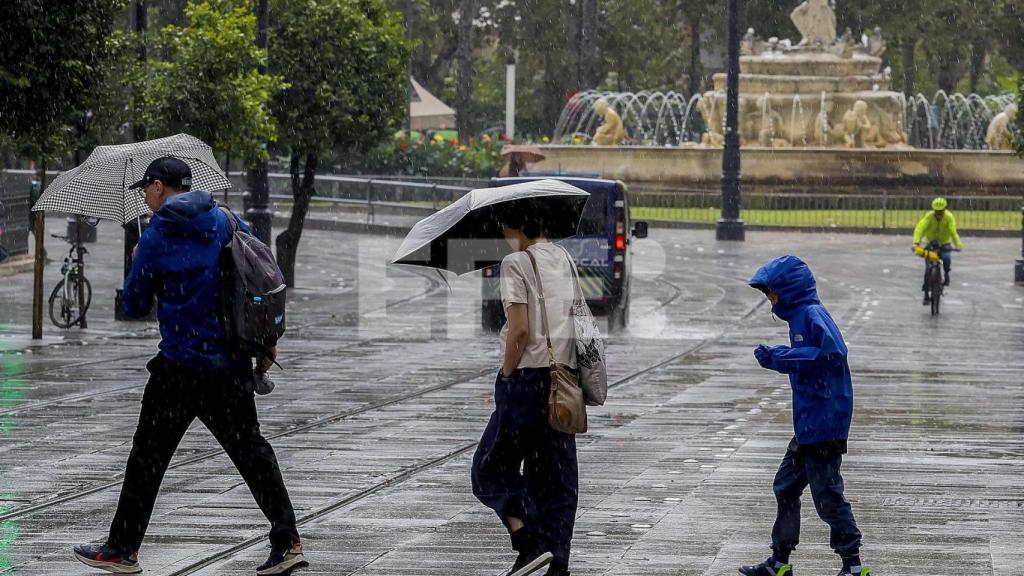 Personas protegiéndose de la lluvia en Sevilla.