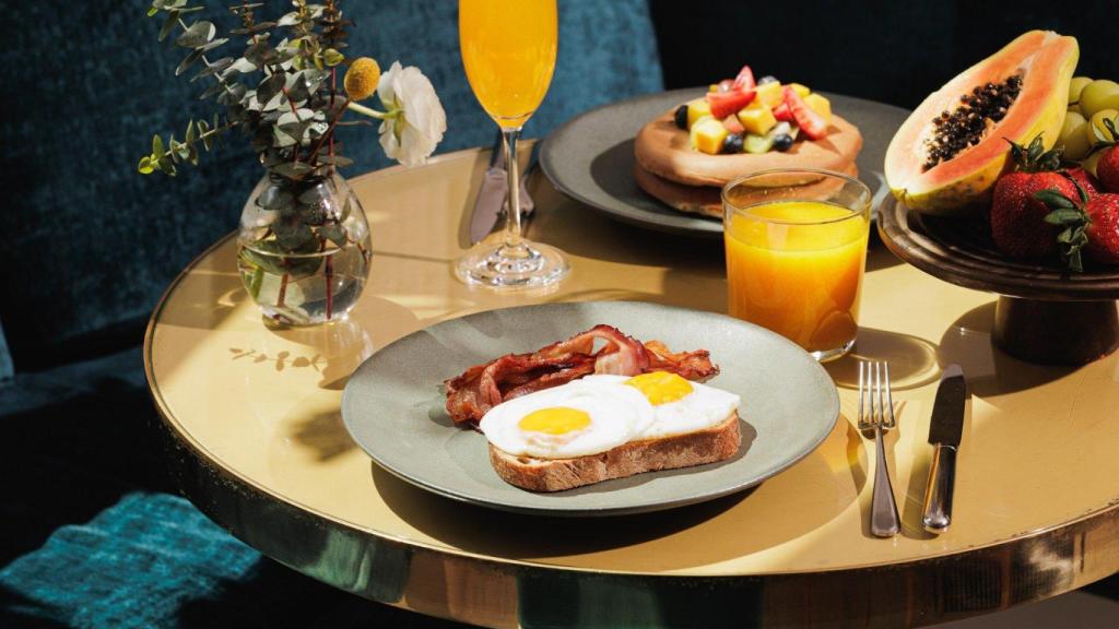 Huevos escalfados sobre tostada de aguacate o pancakes Lumi con fruta.