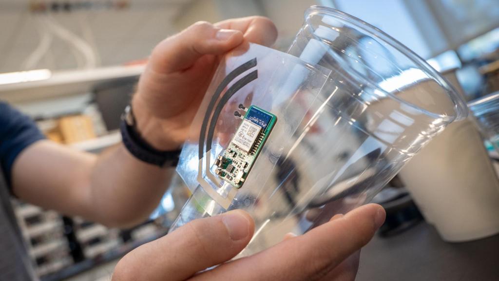 Un investigador pegando la pegatina electrónica en un vaso.