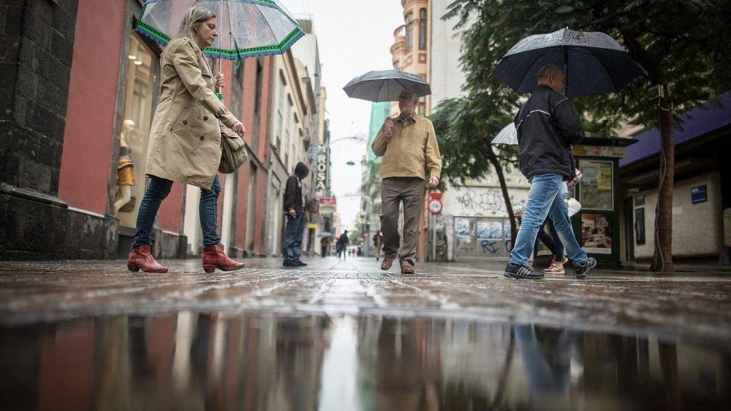 Imagen de archivo de varias personas bajo la lluvia.