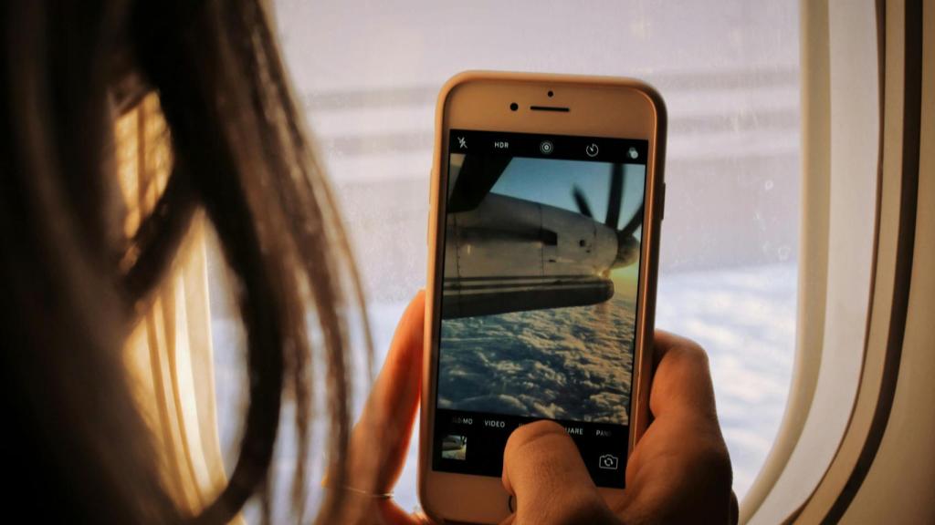 Una persona usando el móvil en el avión