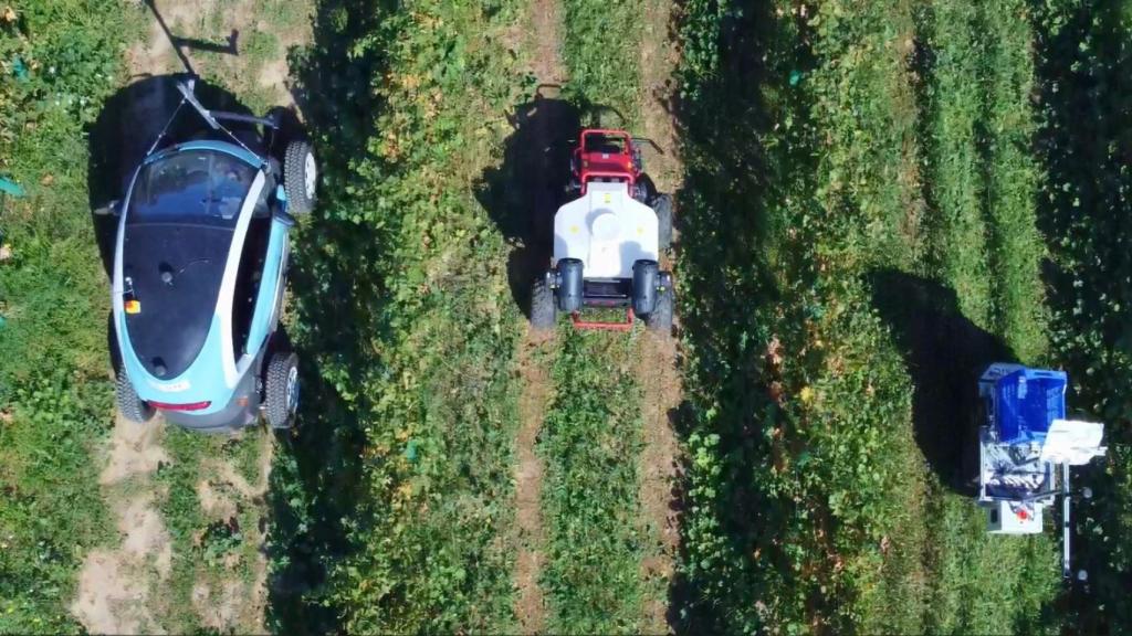 El vehículo eléctrico automatizado junto con robots en una prueba de campo.