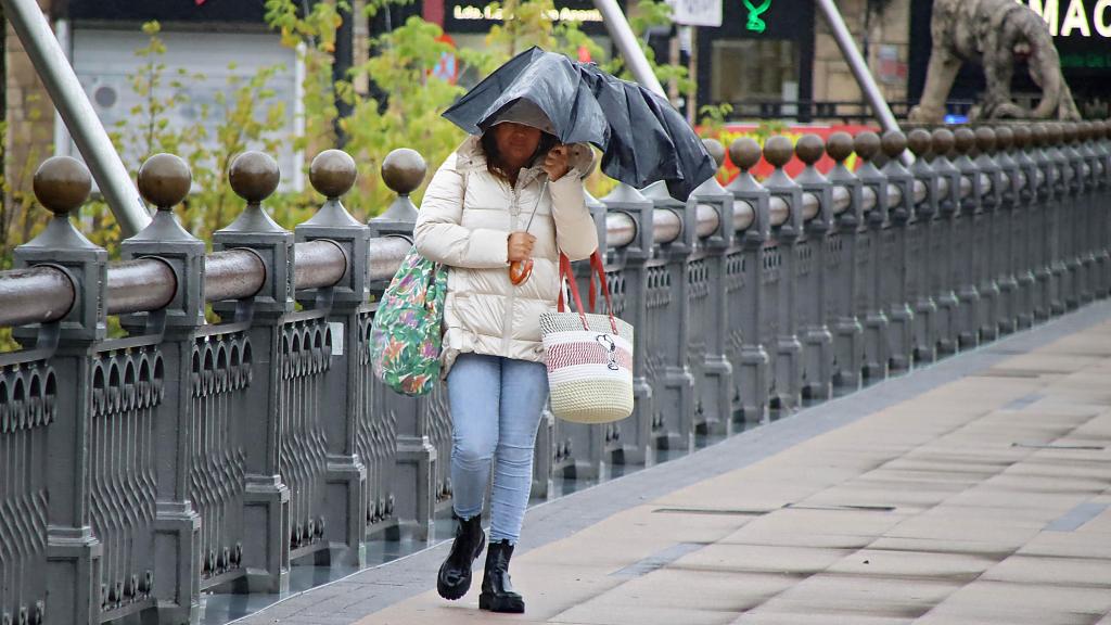 Una mujer se protege del viento en la ciudad de León