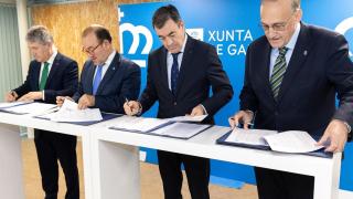 El conselleiro de Educación, Román Rodríguez, firmando un acuerdo con los tres rectores.