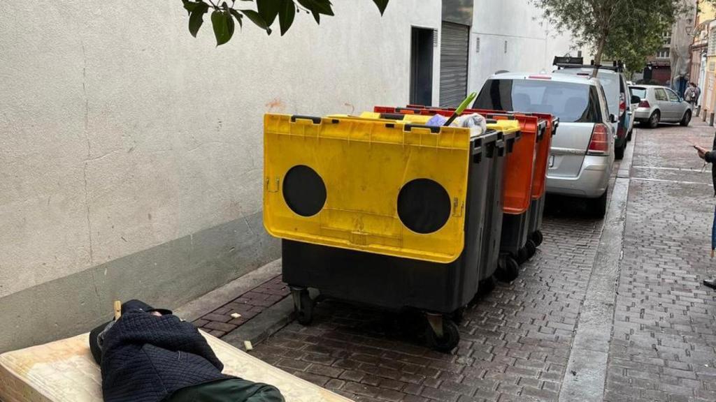 Un hombre durmiendo en un colchón en medio de la calle a plena luz del día
