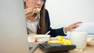 Imagen de archivo de una chica comiendo a la par que trabaja.