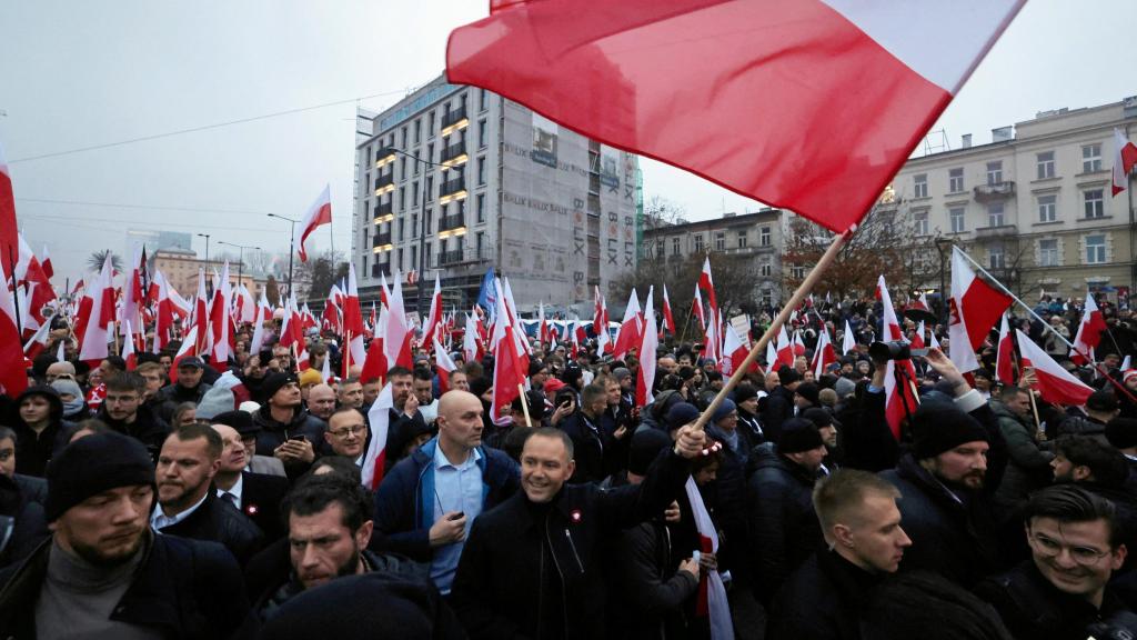 El presidente Karol Nawrocki sostiene una bandera polaca en una marcha por las calles de Varsovia.