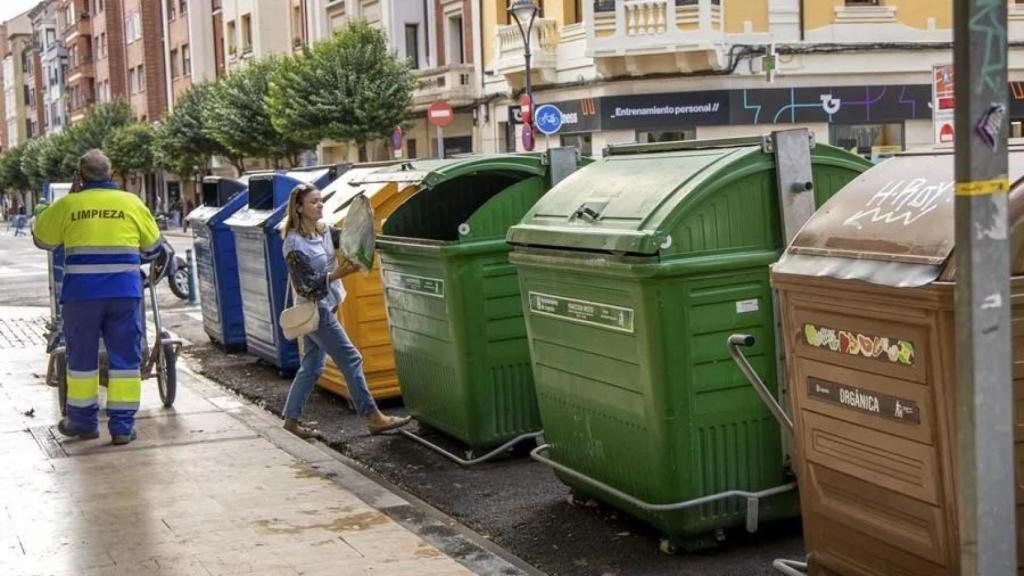 Una mujer tira basura al contenedor.