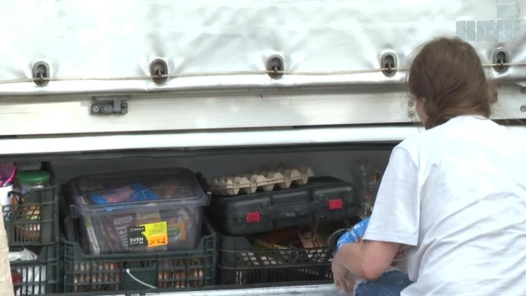 Una persona sacando comida de la despensa de una autocaravana.